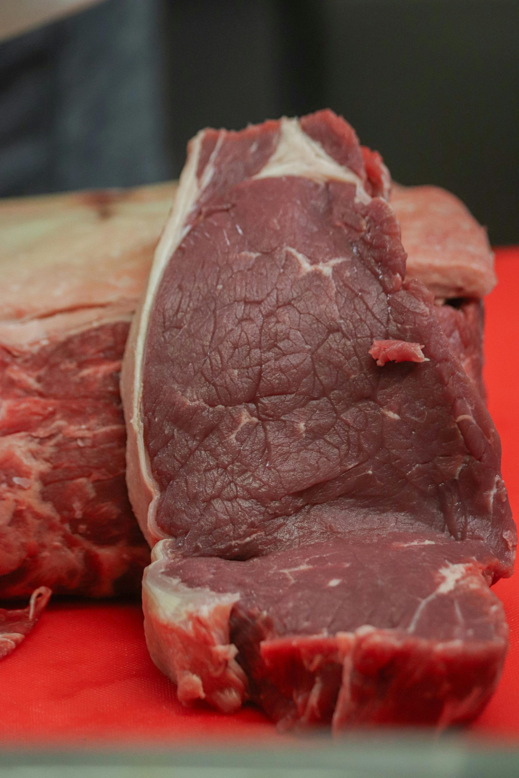 Close-up of a raw steak on a red cutting board, ideal for food photography.
